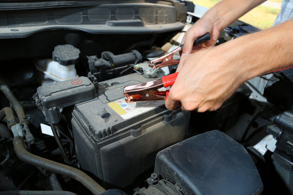 Car mechanic uses battery jumper cables to charge dead battery