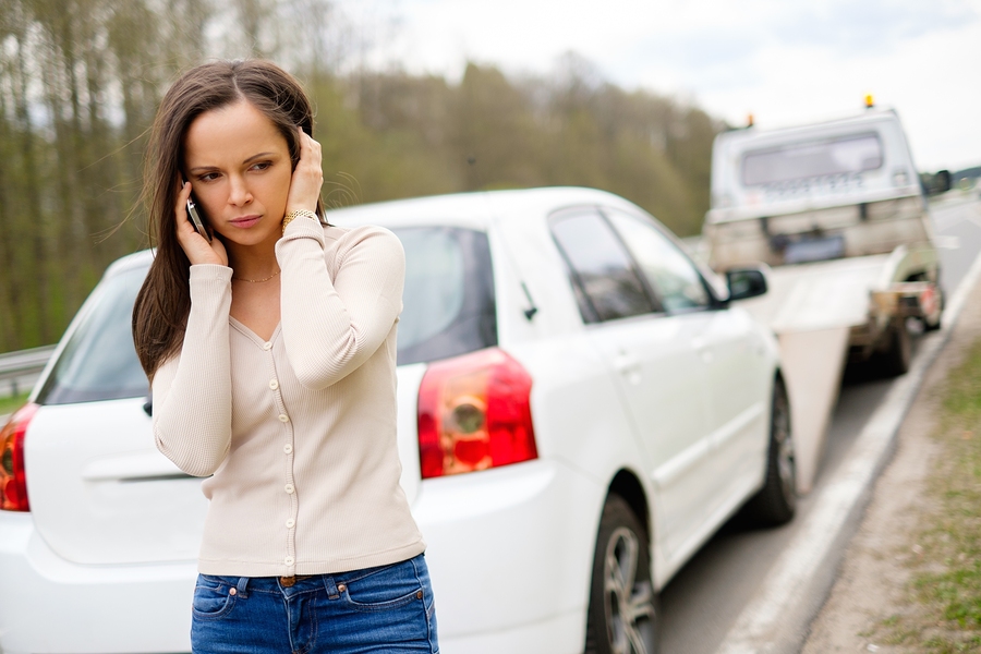 Woman calling while tow truck picking up her car